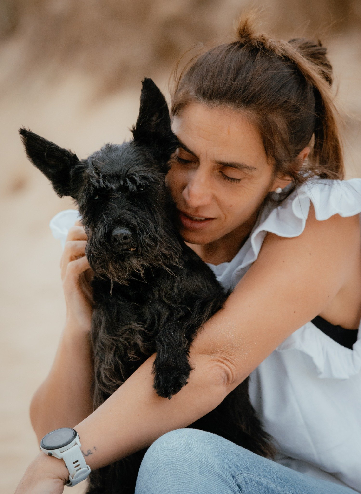 Una mujer abrazando a su perro negro
