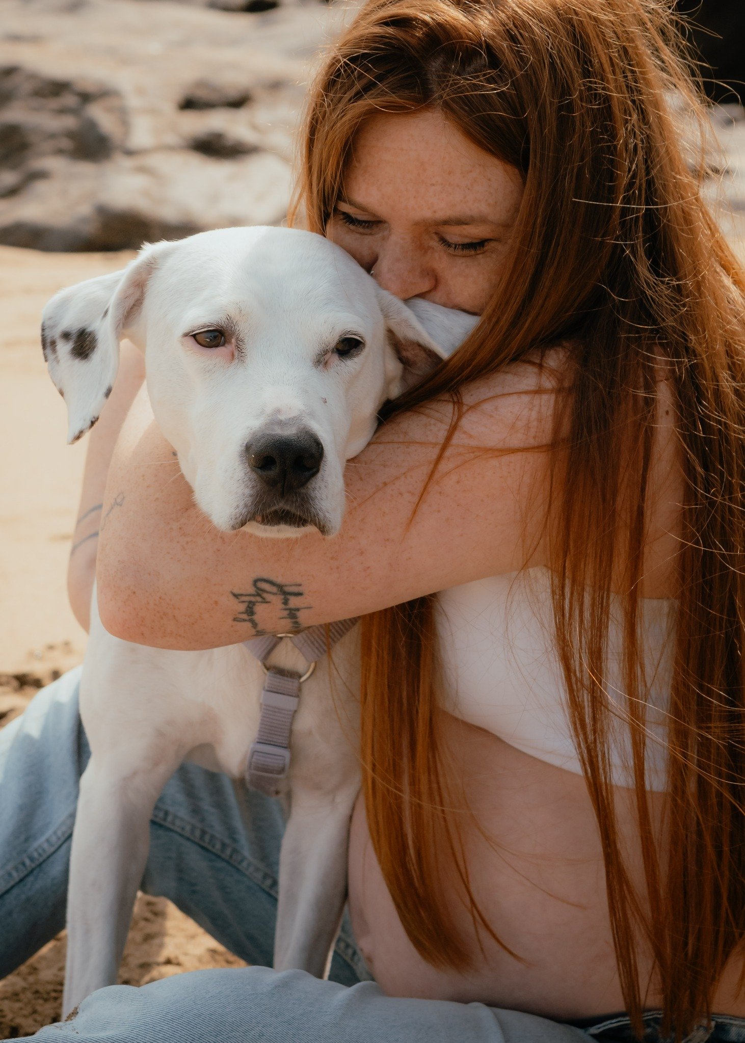 Una mujer besando a su perro blanco